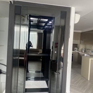Thang máy gia đình vách kính inox gương đen